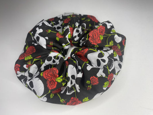 A studio style photo of a giant sized scrunchie with skull and crossbones and red roses.